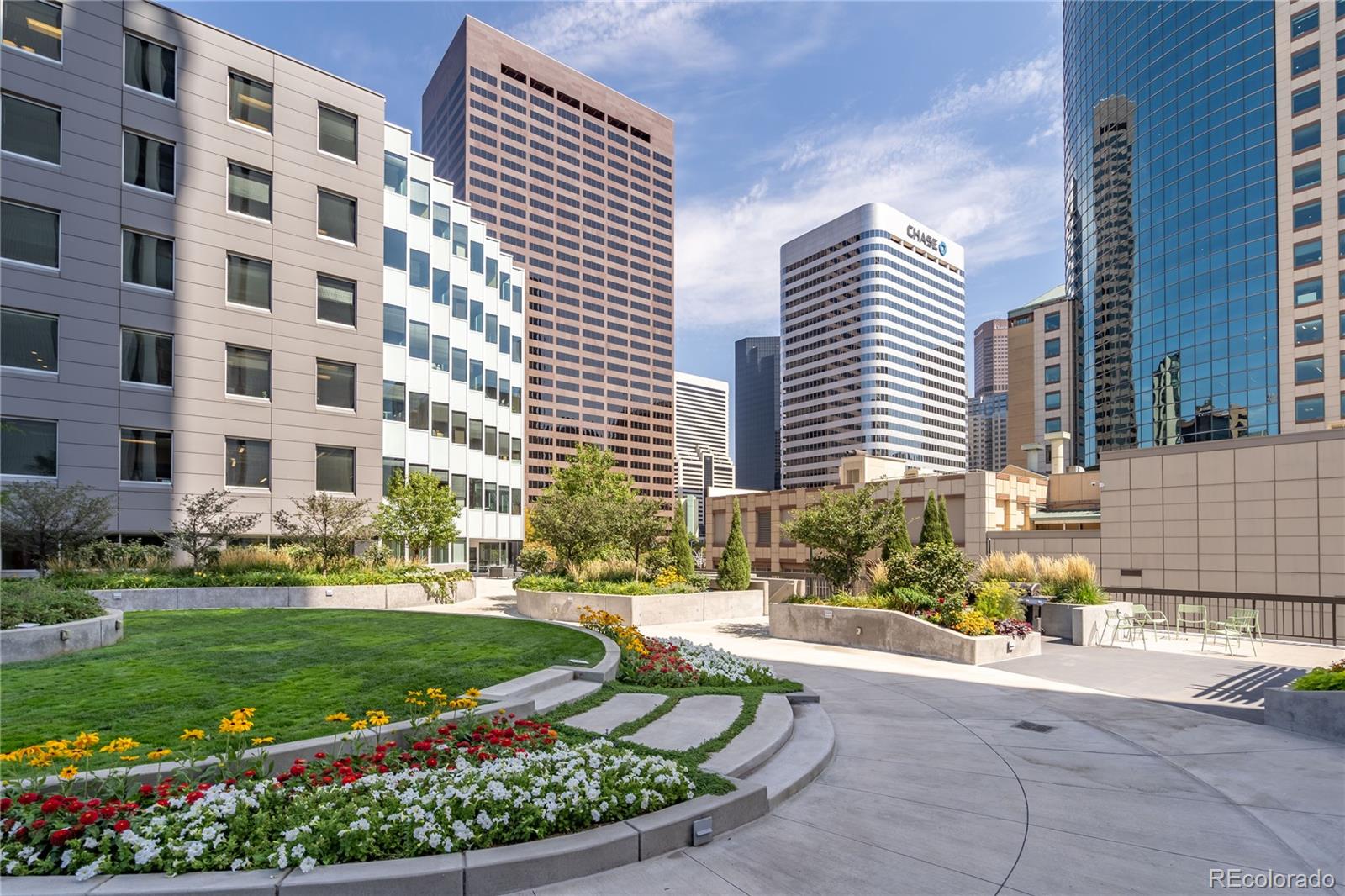 The view outside of the Barclay downtown Denver condos, with lush, colorful landscaping and several tall buildings.