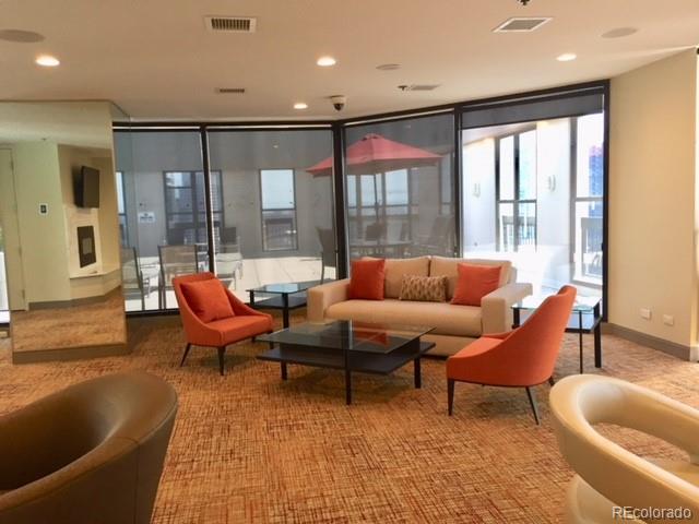 The community room at the Barclay downtown Denver condos, with orange seating against floor to ceiling windows.